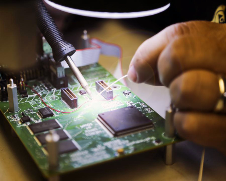 An engineer working on a circuit board within the Electronics Assembly Shop.