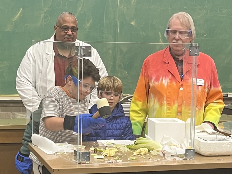 Dale Stille and Vincent Rodgers help a child with a physics demo