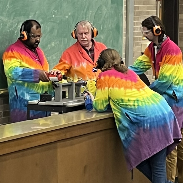 students in lab coats and Dale Stille with a rocket engine demo