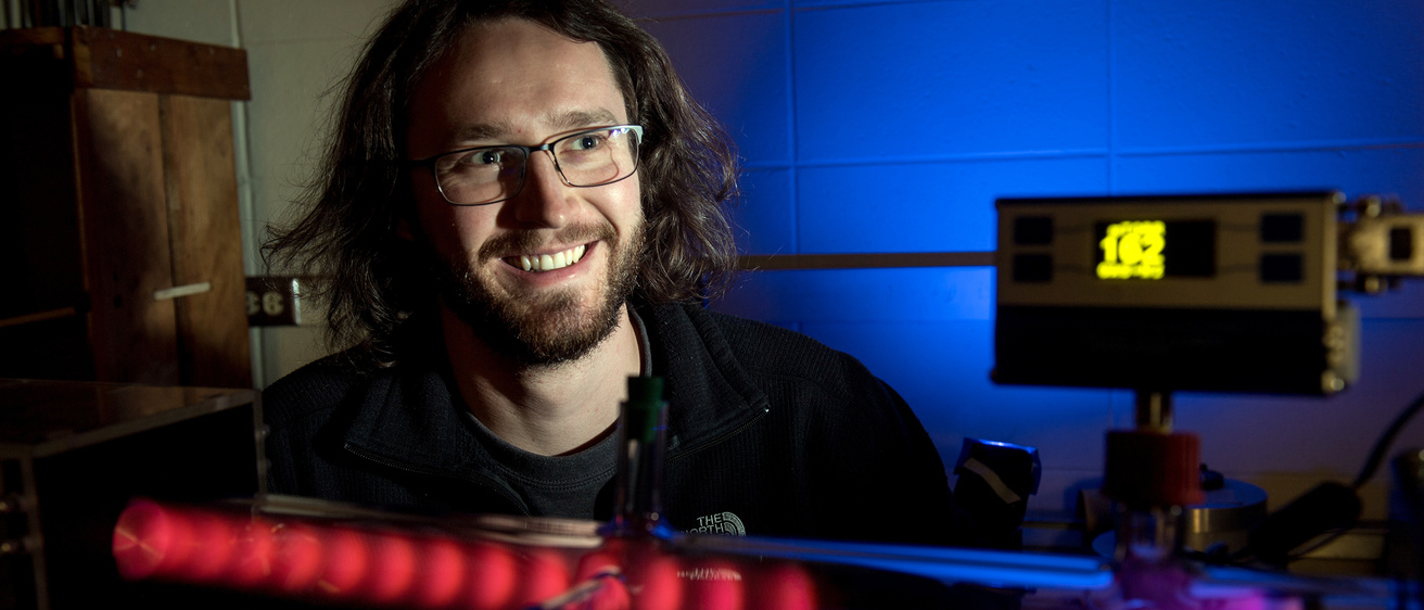 Graduate student Josh Larson with the plasma tube he built.