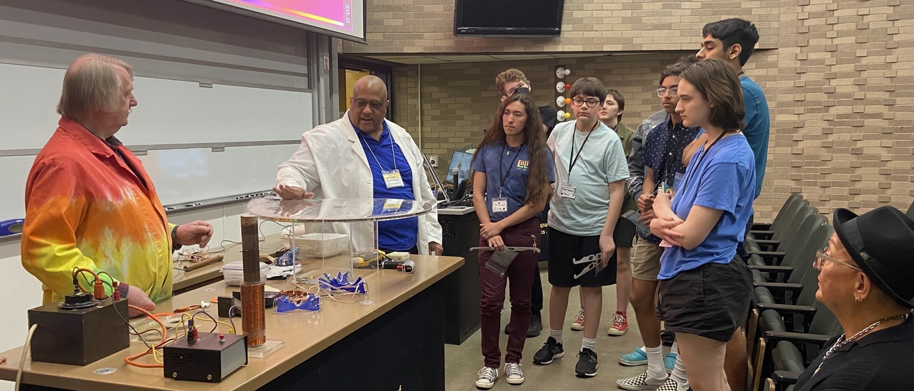 Prof. Vincent Rogers presents a physics demo as NASA's Eddie Gonzales looks on