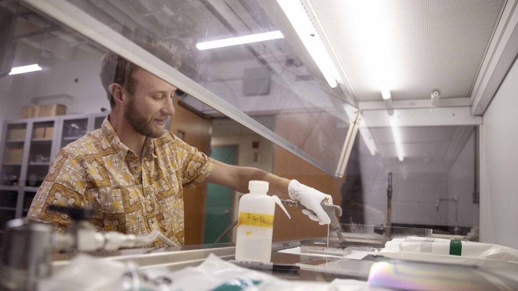 Jacob Payne uses nitrogen to dry off a mirror in a lab
